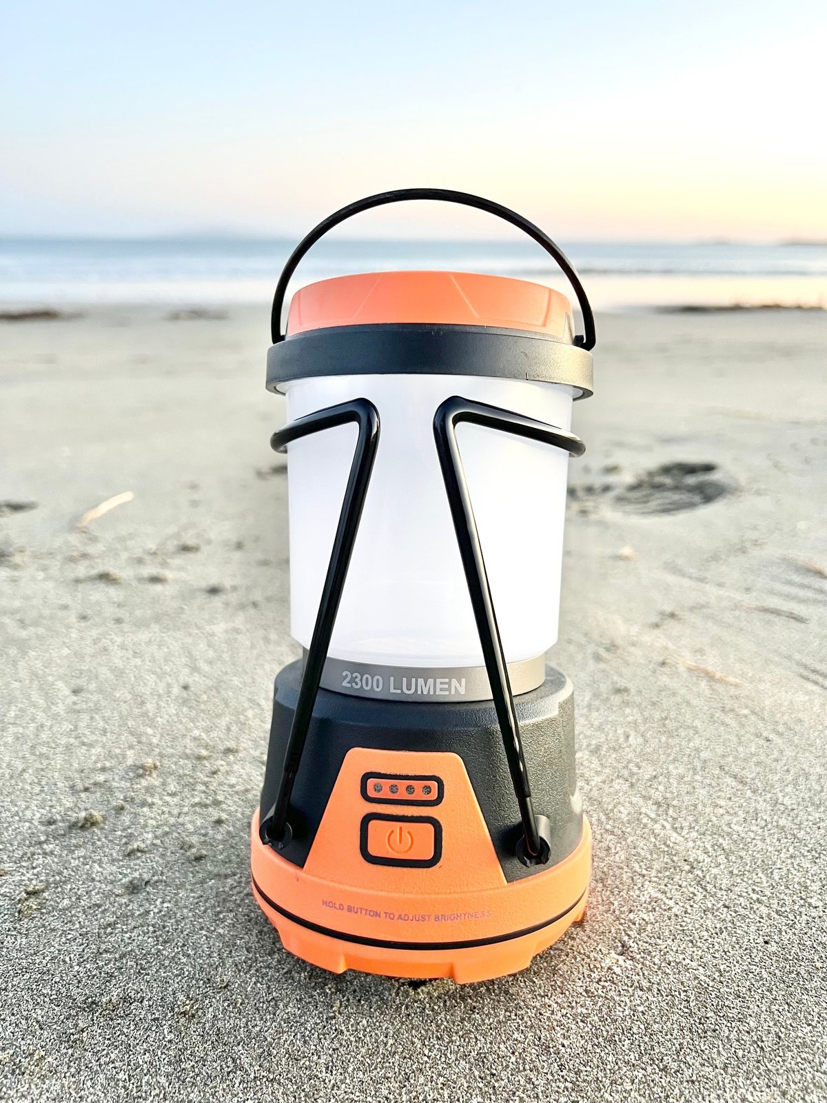 Portable camping lantern photographed on the sand at sunset